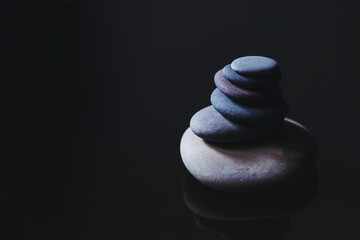 Fototapeta na wymiar Pierres lisses empilées avec fond noir - Galets empilés et espace libre, symbole de zen 