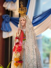 Statue of Virgin Mary praying, hands joined, with a crown. Our Lady of Fatima with flowers in a Catholic church in Thailand