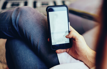 Back view of male checking banking balance on mobile phone connected to home internet