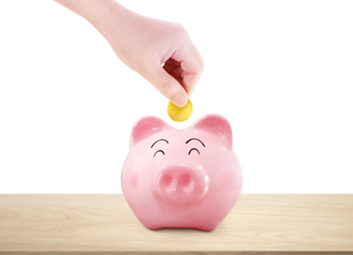 Hand picks up a gold coin and puts it in a piggy bank on a wooden table. PNG transparent