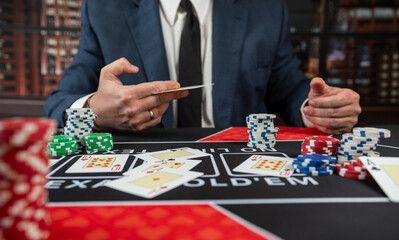 Man in suit hold card and chips play poker at casino - obrazy, fototapety, plakaty