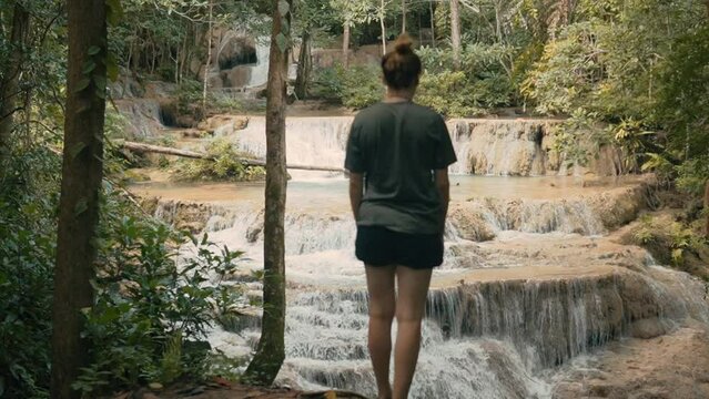 Attracitve Young Woman Hiking Next to Waterfall in Erawan National Park, Thailand