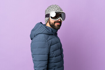 Skier man with snowboarding glasses over isolated purple background