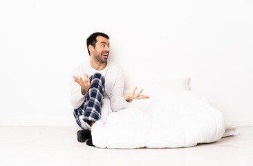 Caucasian man in pajamas sitting on the floor at indoors with surprise expression while looking side