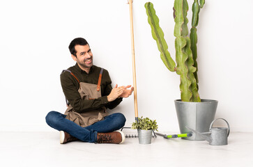 Gardener man sitting on the floor at indoors applauding