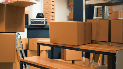 Startup storehouse filled with merchandise to ship to clients, products in cardboard packages used for business development. Empty storage room with carton boxes and stacks of supplies.