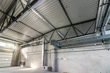 Ventilation pipes in silver insulation material hanging from the ceiling inside new building