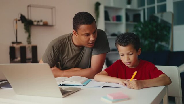 Father helping little son with school homework, cheering up sad kid, support