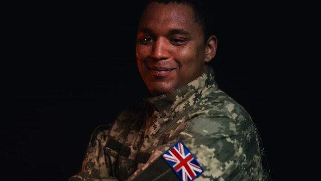 British soldier smiling crossing arms on chest, UK patch on military uniform