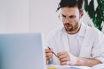 Pensive caucasian male designer concentrated on analyzing information during work