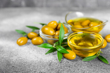 Olive oil in a bottle on texture background. Oil bottle and a bowl with branches and fruits of olives. Place for text. copy space. cooking oil and salad dressing.