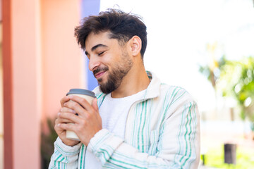 Handsome Arab man at outdoors holding a take away coffee