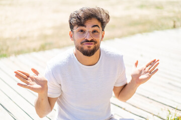 Fototapeta premium Handsome Arab man at outdoors With glasses and having doubts
