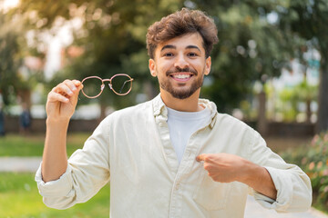 Young Arabian handsome man with glasses at outdoors with surprise facial expression