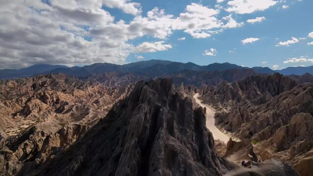 Drone shot flying over sharp rock formations to reveal the Quebrada de las Flechas in Salta, Argentina.