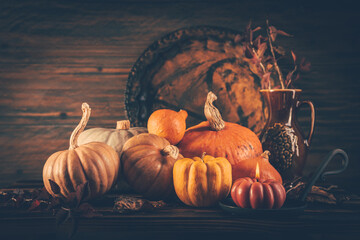 Autumn still life with pumpkins and candles on wooden background. Thankgiving home decoration