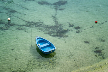 Top view of empty blue fishing boat among transparent turquoise sea waters