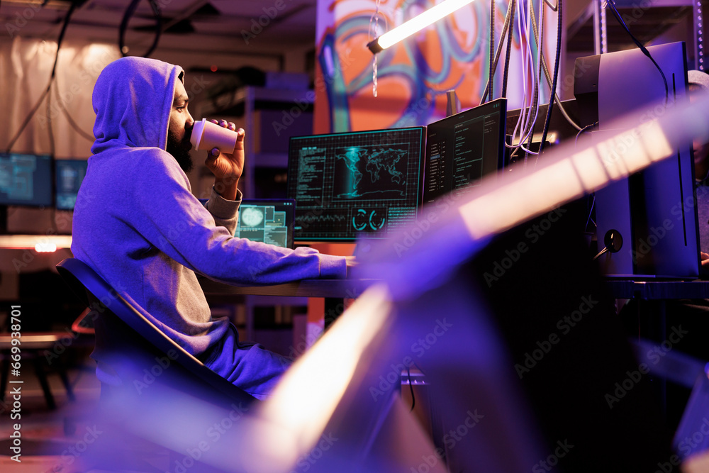 Poster hacker drinking coffee and doing illegal activities on computer late at night. criminal holding beve