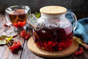 Autumn tea, berry vitamin seasonal drink. Viburnum and cup of healthy viburnum tea on a wood background.