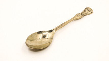 a shiny, clean and old antique bronze metal spoon used by royalty displayed for auction isolated in a white background 