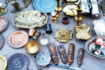 Vintage copper and metal antiques, tableware, souvenirs on a counter at a street flea market. Antique items