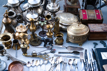 Vintage copper and metal antiques, tableware, jugs, trays, plates, figurines on a counter at a street flea market in Tbilisi. Antique dishes