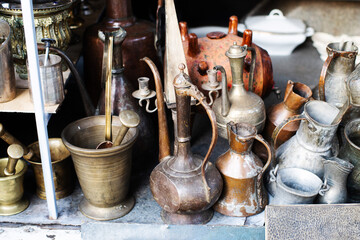 Vintage copper and metal antiques, tableware, jugs, trays, plates, figurines on a counter at a street flea market in Tbilisi. Antique dishes