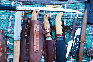 Vintage antiques, handmade knives in leather sheaths on a counter at a street flea market. Antique items