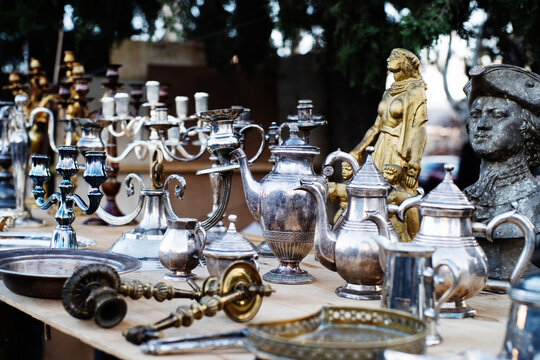 Vintage copper and metal antiques, tableware, jugs, trays, plates, figurines on a counter at a street flea market in Tbilisi. Antique dishes