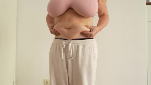 unrecognizable figure woman showing sagging fat folds on stomach