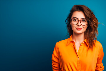 a young woman with glasses wear a orange top on blue background  - obrazy, fototapety, plakaty