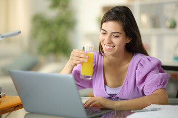 Happy student drinking orange juice at home