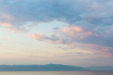 Beautiful fluffy clouds painted in pastel colors at sunrise. Pink and light blue. Multicolor background or wallpaper
