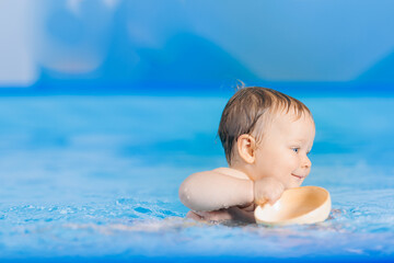 Fototapeta na wymiar Portrait happy baby girl play with toy in swimming pool, teaching small swimmer. Concept healthcare sport for infant