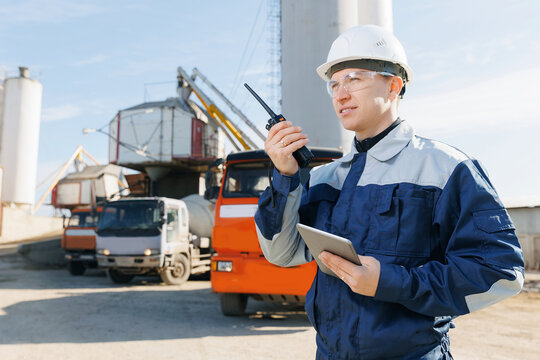 Banner cement plant or concrete factory. Engineer man in uniform with tablet computer and radio walkie controls loading to mixer truck