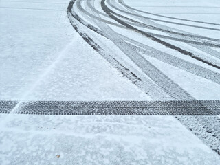 Dynamic car tread marks on the snow. Early winter. Energy and expression of movement. Black and white wheel print graphics