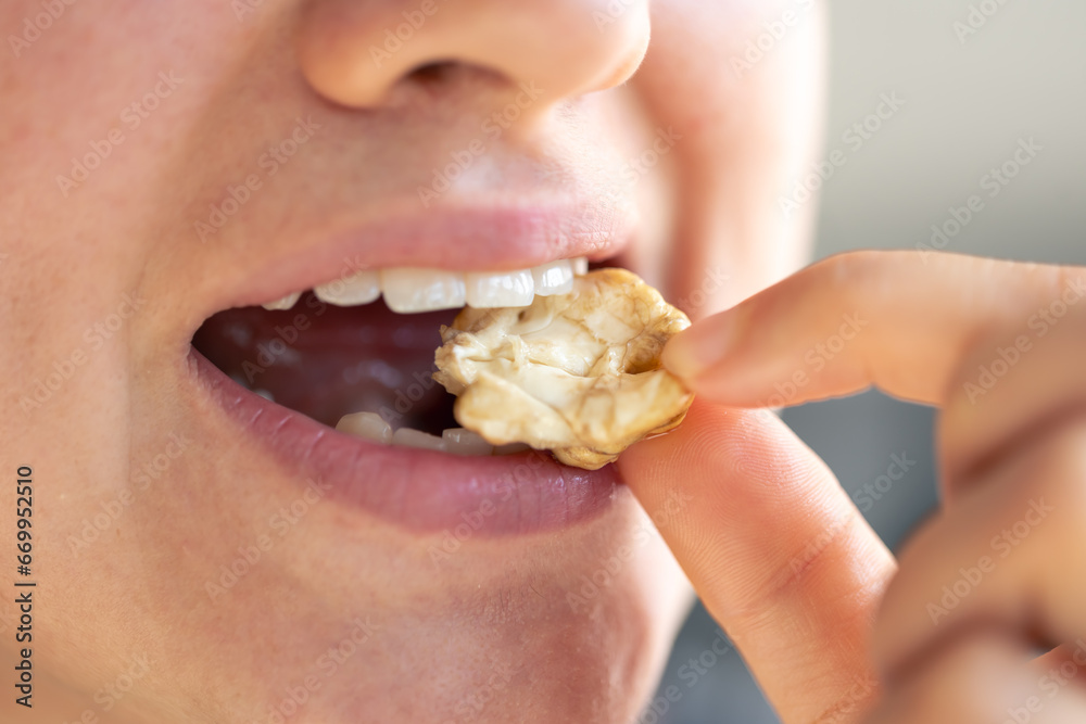 Wall mural detailed shot of a woman bites walnut.