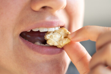 Detailed shot of a woman bites walnut.