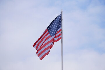 American Flag . USA national flag waving on wind against blue sky. Slow motion
