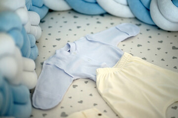 The child's clothes lie on the cot. - obrazy, fototapety, plakaty