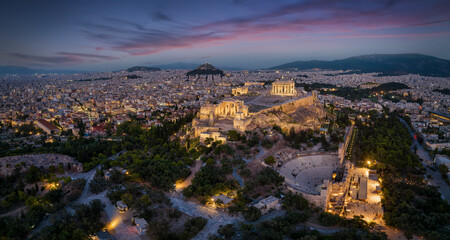Fototapeta premium Aerial view of the illuminated skyline and ancient ruins at the Acropolis of Athens, Greece, with Parthenon Temple and Odeon of Herode theatre during evening