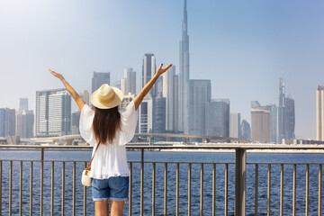 A happy tourist woman enjoys the view of the modern skyline of Dubai, UAE