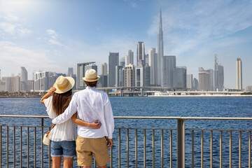 A elegant tourist couple on a sightseeing tour enjoys the view of the skyline of Dubai, UAE
