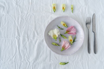 Decor of flowers and dishes on a white tablecloth. Pink and white flowers on fabric.