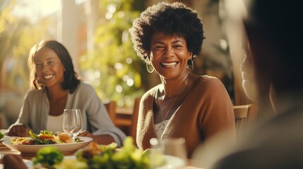 Cheerful African American lady having Thanksgiving lunch with her family and serving serving of mixed greens at feasting table.