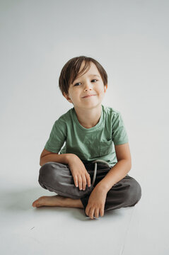 Smiling Boy Sitting Against White Background