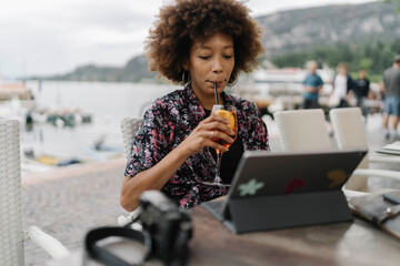 Young freelancer drinking and working on tablet PC in bar