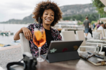 Happy young freelancer working on tablet PC at table in bar