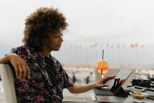 Smiling young freelancer touching and using tablet PC at table