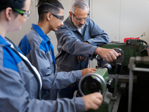 Instructor giving lathe machine training to trainees at workshop